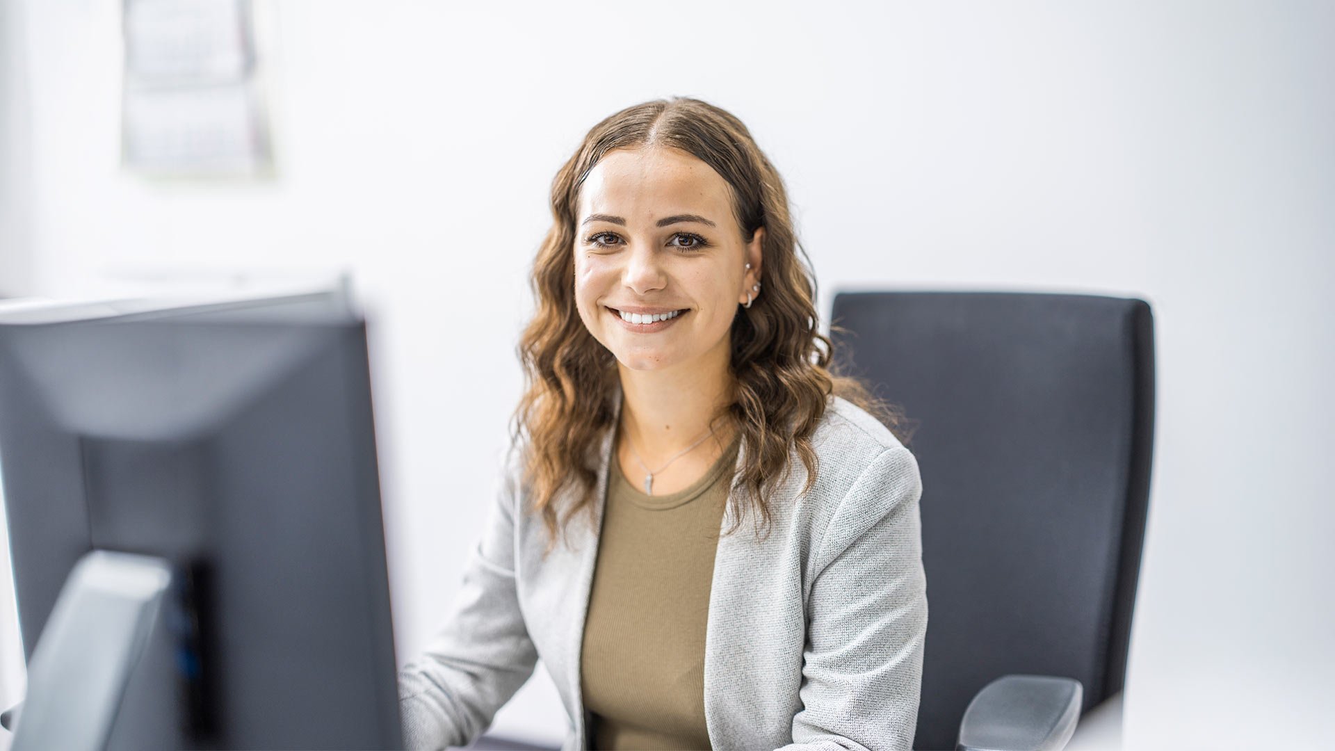 Women-employee-smiling-sitting-at-desk-koester