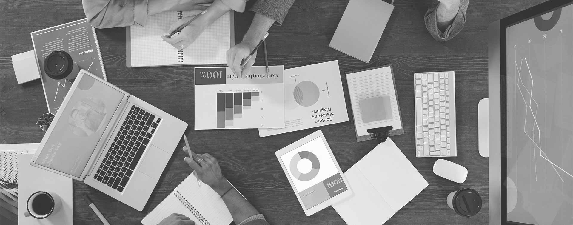 Value-innovation-group-sitting-at-work-desk-with-laptop-and-computer Value-innovation-group-sitting-at-work-desk-with-laptop-and-computer